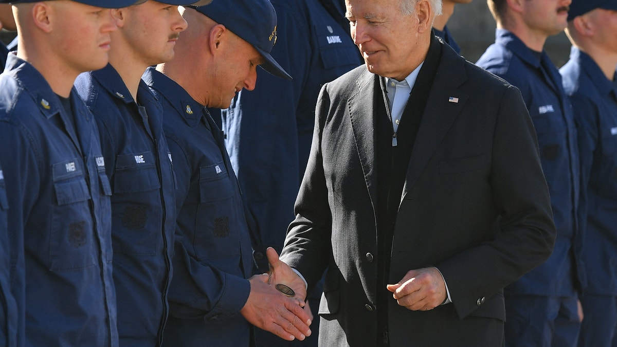 President Biden hands a service member a challenge coin as he greets members of the Coast Guard at U.S. Coast Guard Station Brant Point.