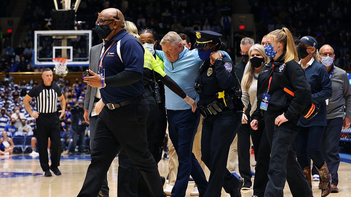 DURHAM, NORTH CAROLINA - NOVEMBER 22: Head coach Duggar Baucom of the Citadel Bulldogs is helped off of the floor after a medical incident during the first half of their game against the Duke Blue Devils at Cameron Indoor Stadium on November 22, 2021 in Durham, North Carolina.
