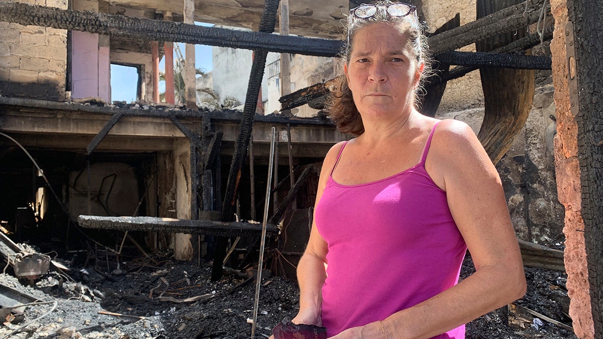 Emilie holds her burned passport in her charred home following riots in Pointe-a-Pitre, Guadeloupe island, on Sunday, Nov. 21, 2021. 