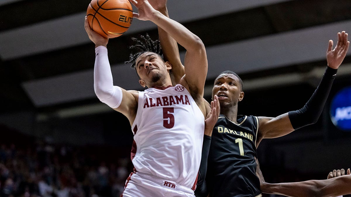 Alabama guard Jaden Shackelford (5) grabs a rebound with Oakland forward Jamal Cain (1) in pursuit during the second half of an NCAA college basketball game, Friday, Nov. 19, 2021, in Tuscaloosa, Ala.
