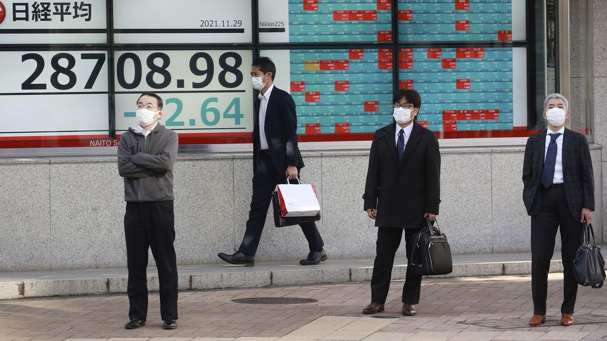 People stand by an electronic stock board of a securities firm in Tokyo on Monday.