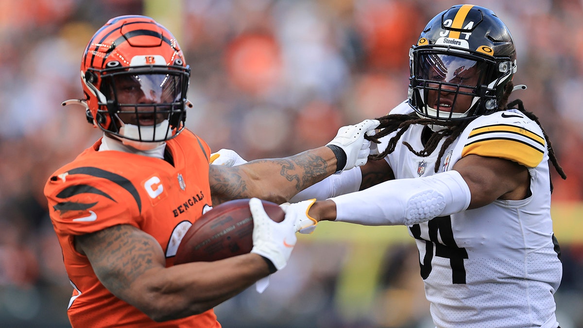 Cincinnati Bengals running back Joe Mixon, left, runs the ball against Pittsburgh Steelers safety Terrell Edmunds (34) during the second half of an NFL football game, Sunday, Nov. 28, 2021, in Cincinnati. 