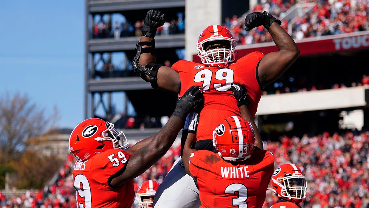 Georgia defensive lineman Jordan Davis (99) is lifted into the air by running back Zamir White (3) and offensive lineman Justin Shaffer (54) after scoring a touchdown in the first half of an NCAA college football game against Charleston Southern, Saturday, Nov. 20, 2021, in Athens, Ga..