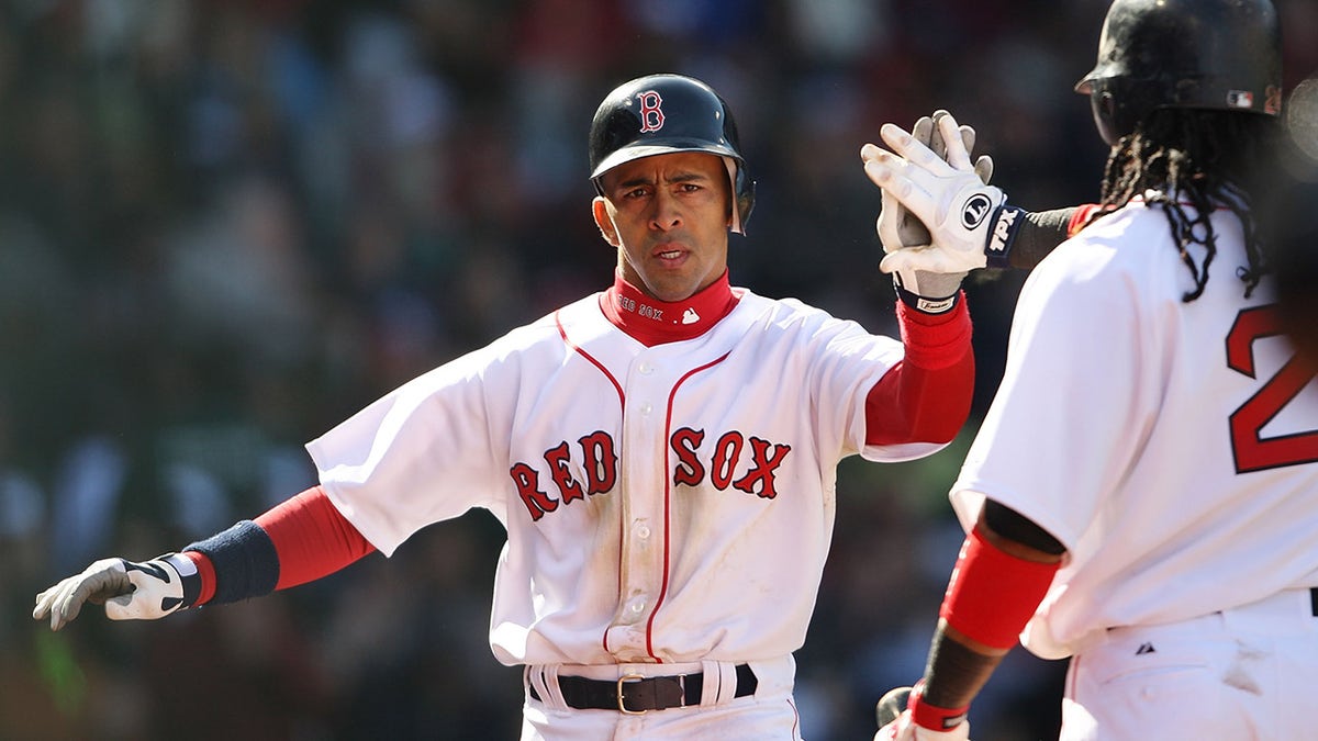 Julio Lugo of the Red Sox is congratulated by teammate Manny Ramirez after scoring against the Detroit Tigers on April 8, 2008, during opening day at Fenway Park in Boston, Massachusetts.