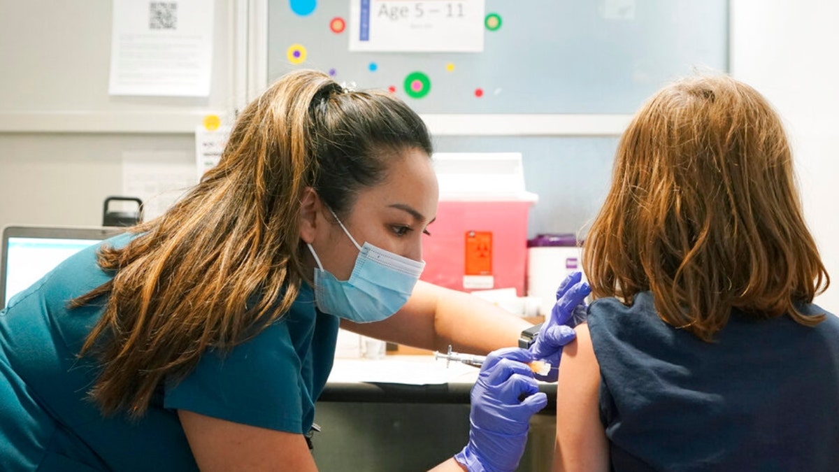 Courtney Martin, left, a nurse at the University of Washington Medical Center, gives the first shot of the Pfizer COVID-19 vaccine to Ani Hahn, 7, Tuesday, Nov. 9, 2021.