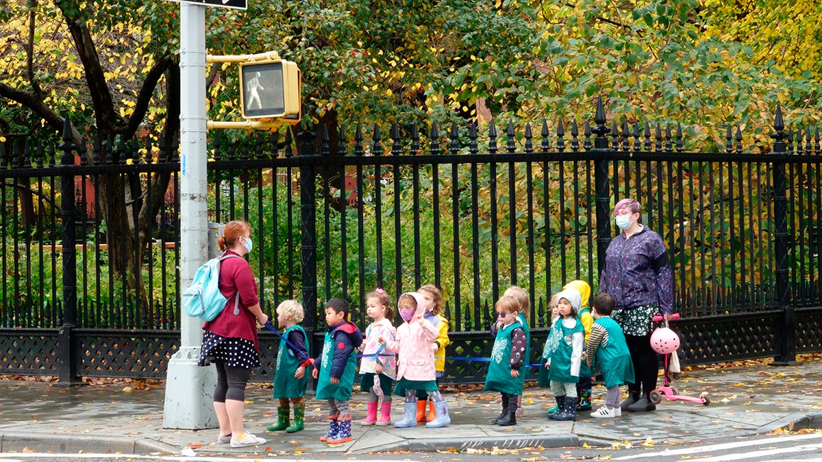 A line of preschool children crossing the street with a teacher