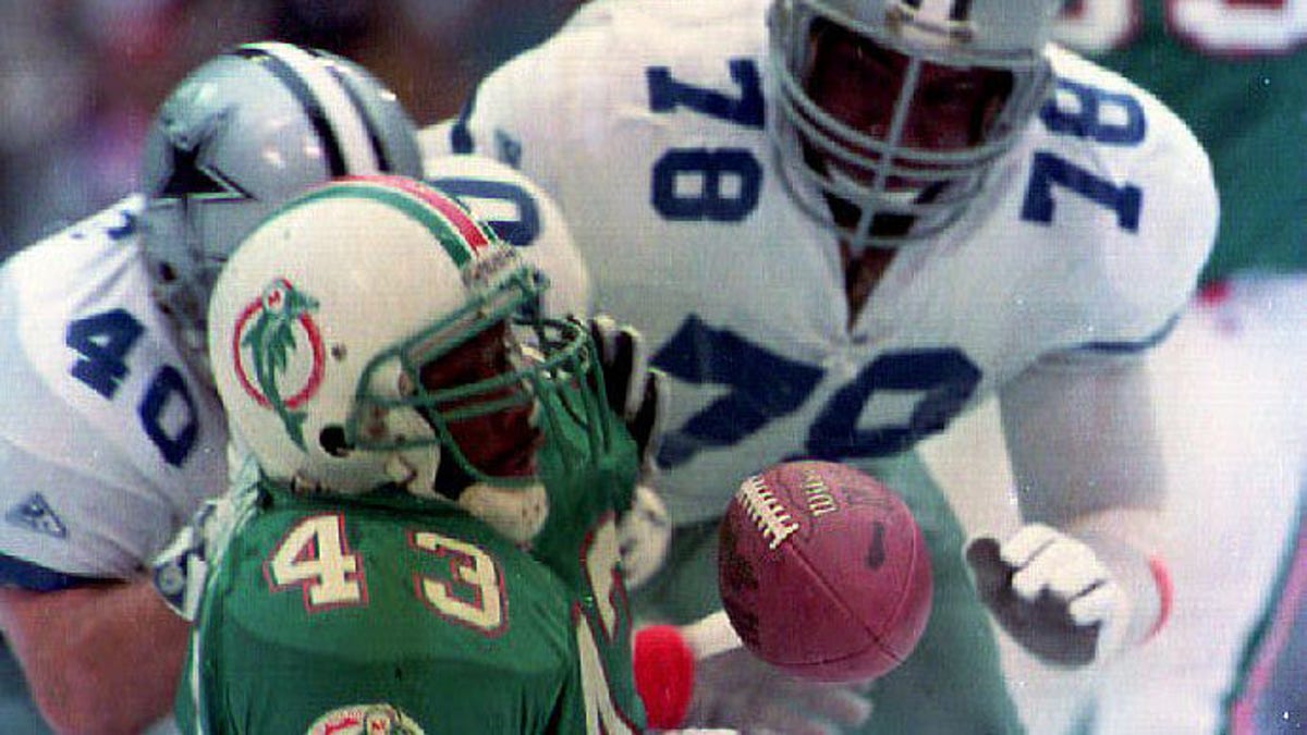 Miami Dolphins running back Terry Kirby (43) loses the ball while being brought down by the Dallas Cowboys' Brock Marion (31), Leon Lett (78) and Bill Bates (40) during first quarter action Nov. 25, 1993 in Texas. 