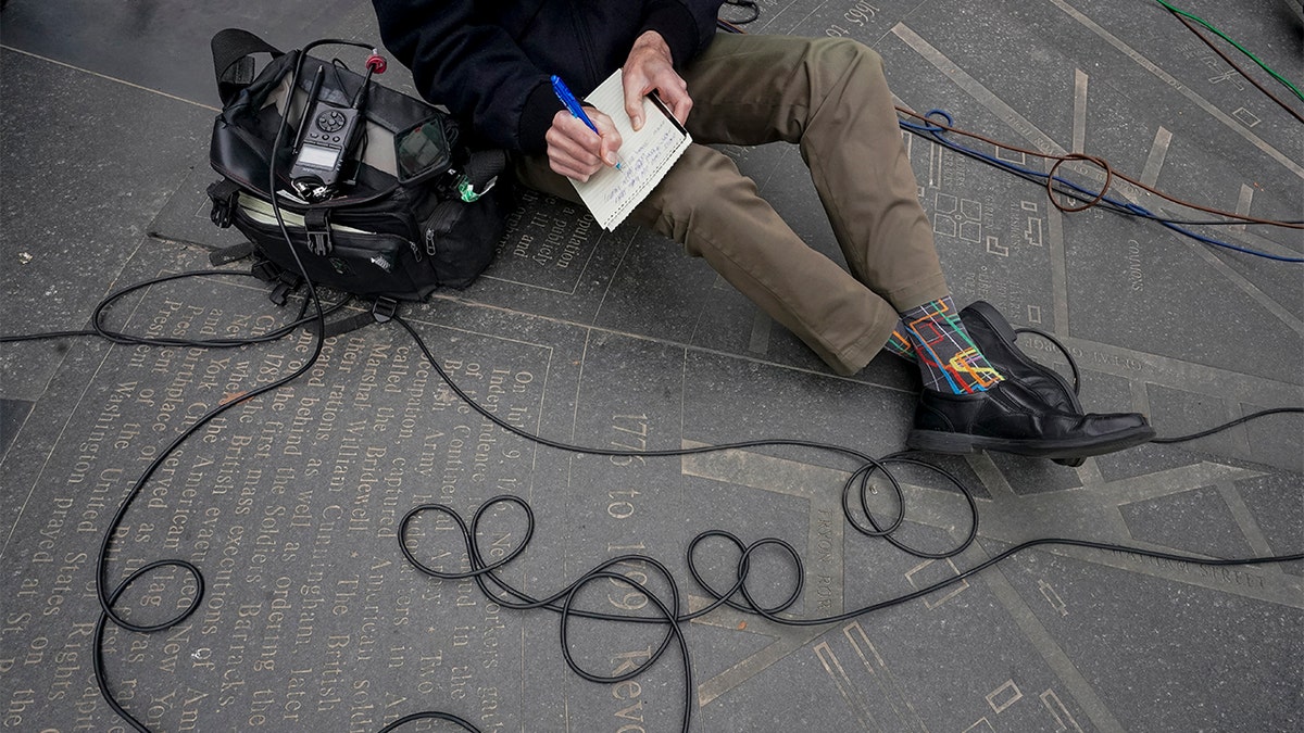 FILE - WCBS Newsradio 880 reporter Peter Haskell wears New York subway map themed socks while taking notes during a news conference in New York on March 24, 2021.