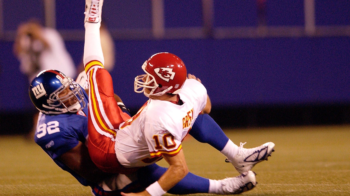 Michael Strahan (92) of the New York Giants tosses Trent Green (10) of the Kansas City Chiefs to the ground on Aug. 13, 2004, at Giants Stadium in East Rutherford, New Jersey.