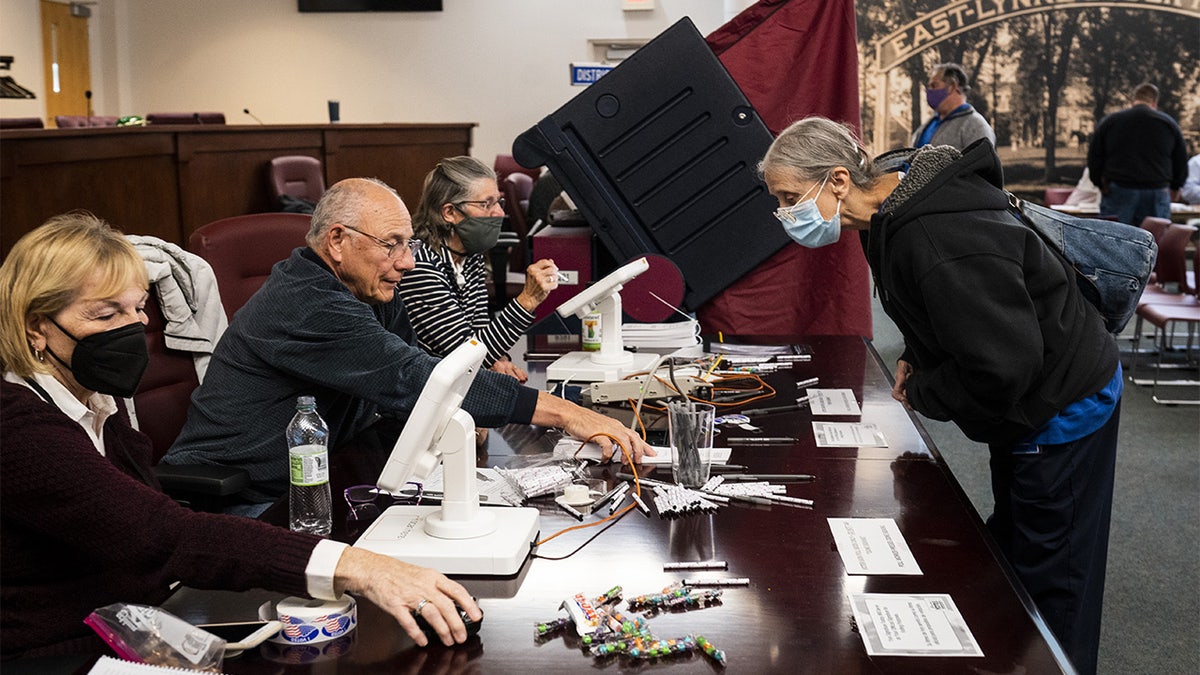 Election officials help check in voters at a polling location in Raritan, New Jersey, U.S., on Tuesday, Nov. 2, 2021. New Jersey voters lean Democratic, but frustration over high taxes has kept Democrats from winning second terms as governor for more than four decades.