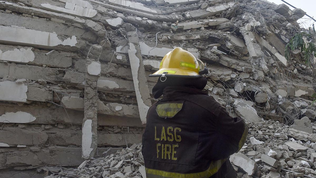 A fire fire fighter stand in the rubble of a 21-story building under construction that collapsed at Ikoyi district of Lagos, on Nov. 1.