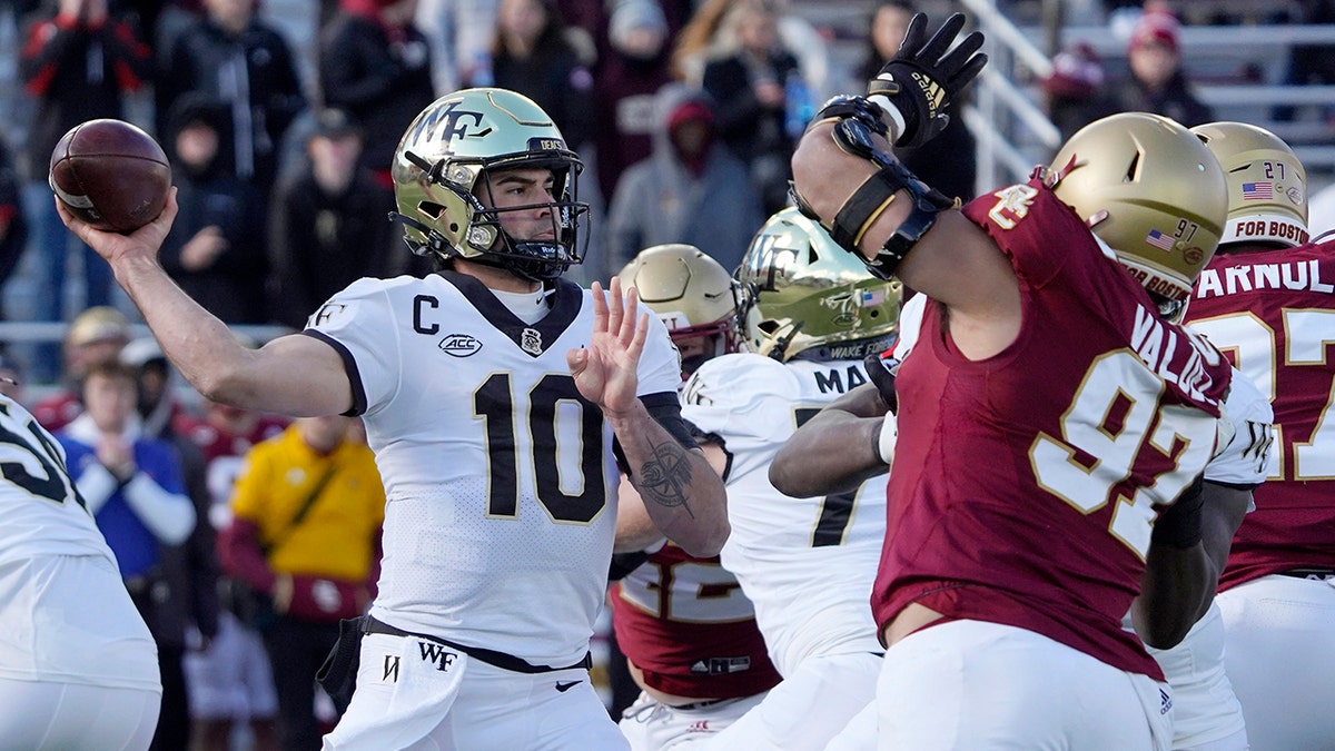 Wake Forest quarterback Sam Hartman (10) passes under pressure from Boston College defensive end Marcus Valdez (97) during the first half of an NCAA college football game, Saturday, Nov. 27, 2021, in Boston.