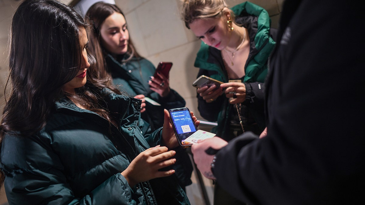 A group of women show their COVID passports as they enter La Belle Angele nightclub on Nov. 25, 2021, in Edinburgh, Scotland. 