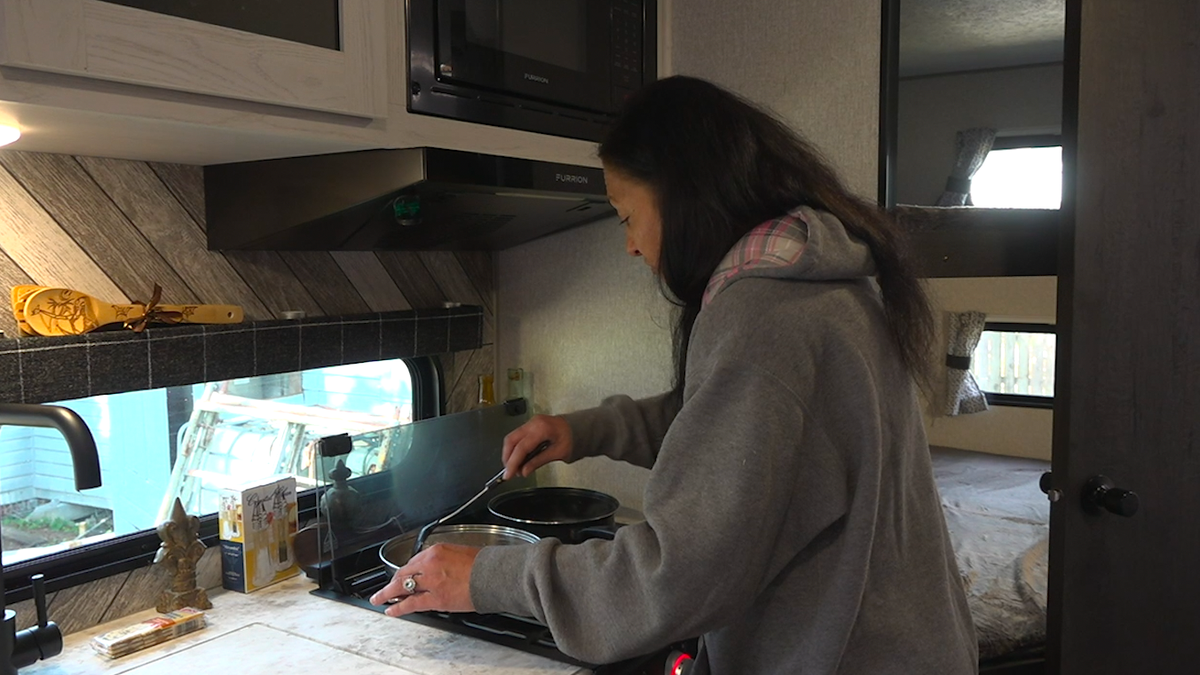 Cheryl Calvaruso cooks a meal in her state-provided travel trailer.