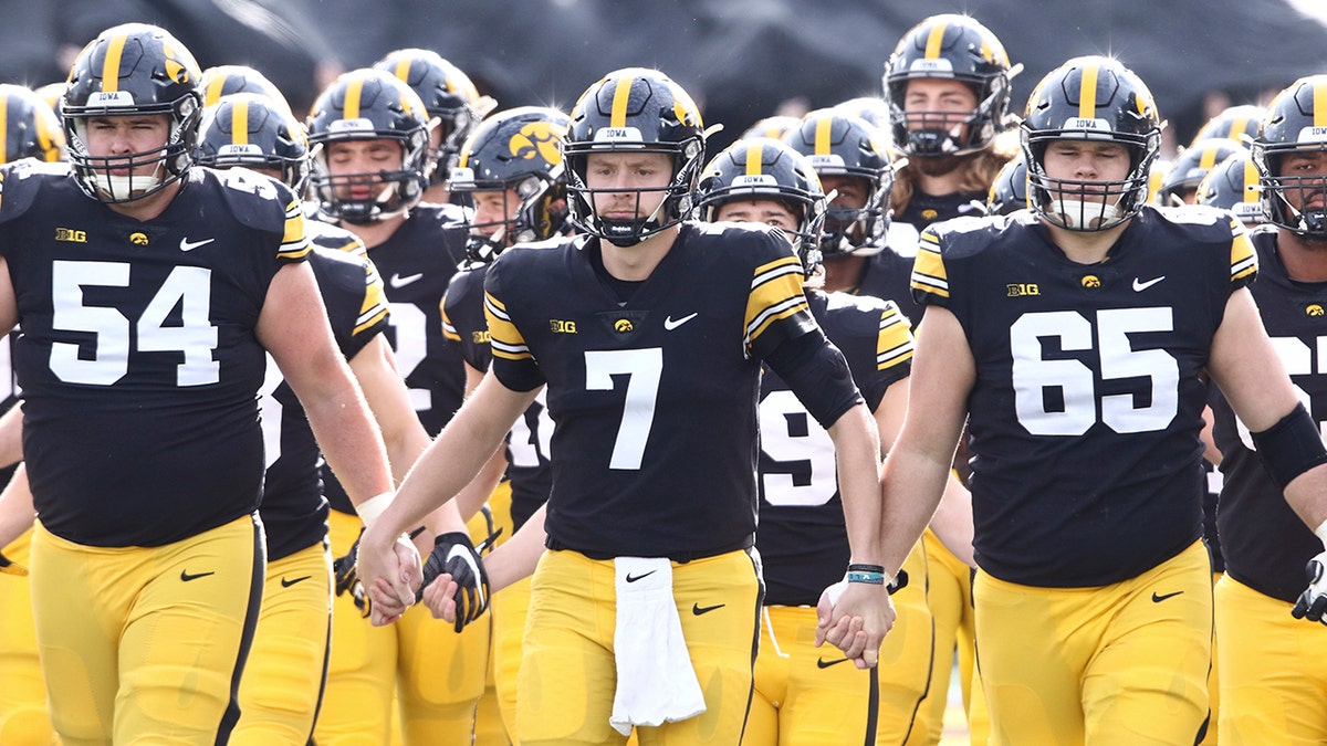 IOWA CITY, IOWA- NOVEMBER 20:  Quarterback Spencer Petras #7, offensive lineman Matt Fagan #54 and offensive lineman Tyler Linderbaum #65 of the Iowa Hawkeyes walksout with teammates before the match-up against the Illinois Fighting Illini at Kinnick Stadium on November 20, 2021 in Iowa City, Iowa. 