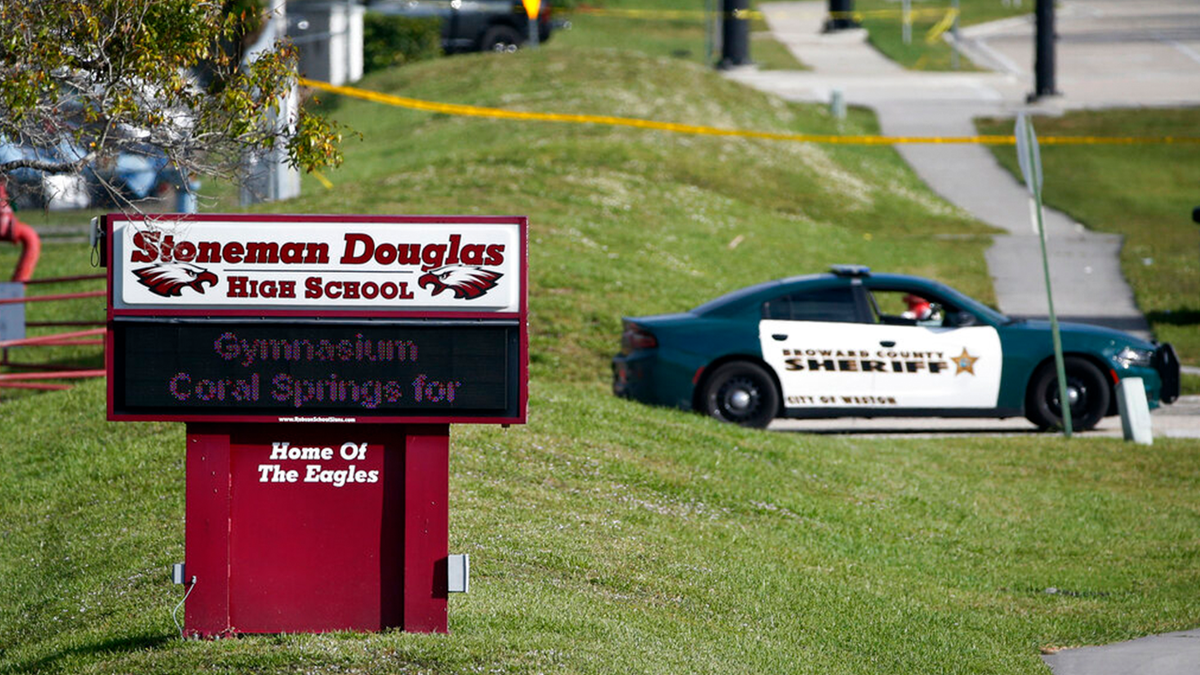 Police car and crime tape blocking entrance of Marjory Stoneman Douglas High School