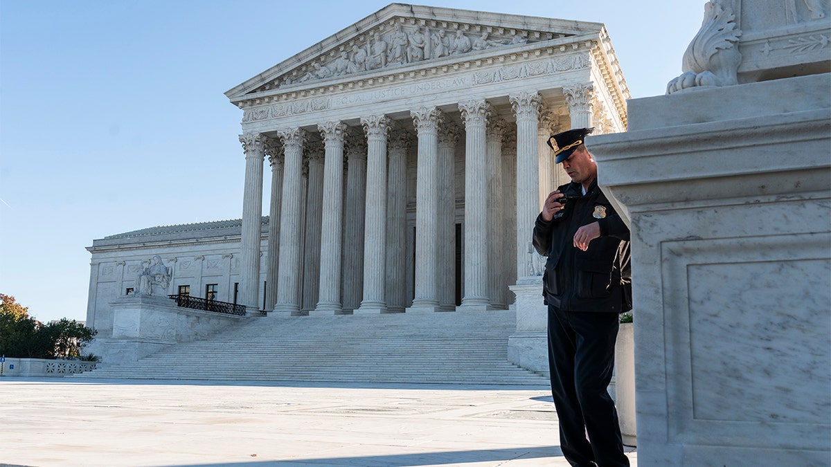 Police officer maintains watch during demonstration by victims of gun violence in front of the Supreme Court 
