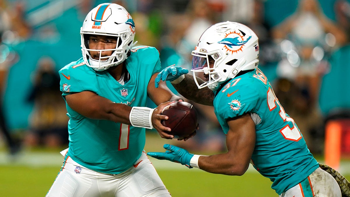 Miami Dolphins quarterback Tua Tagovailoa (1) hands the ball to running back Myles Gaskin (37) during the second half of an NFL football game against the Baltimore Ravens, Thursday, Nov. 11, 2021, in Miami Gardens, Fla.