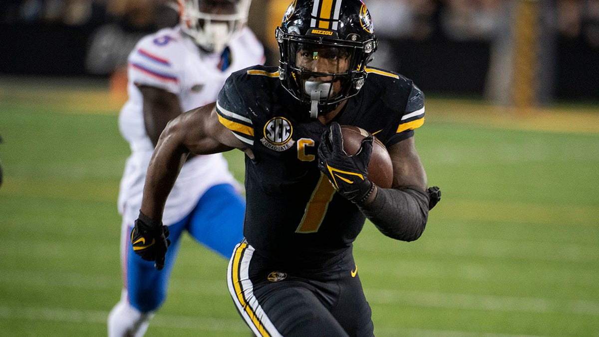 Missouri running back Tyler Badie, right, scores a touchdown during overtime of an NCAA college football game against Florida, Saturday, Nov. 20, 2021, in Columbia, Mo.