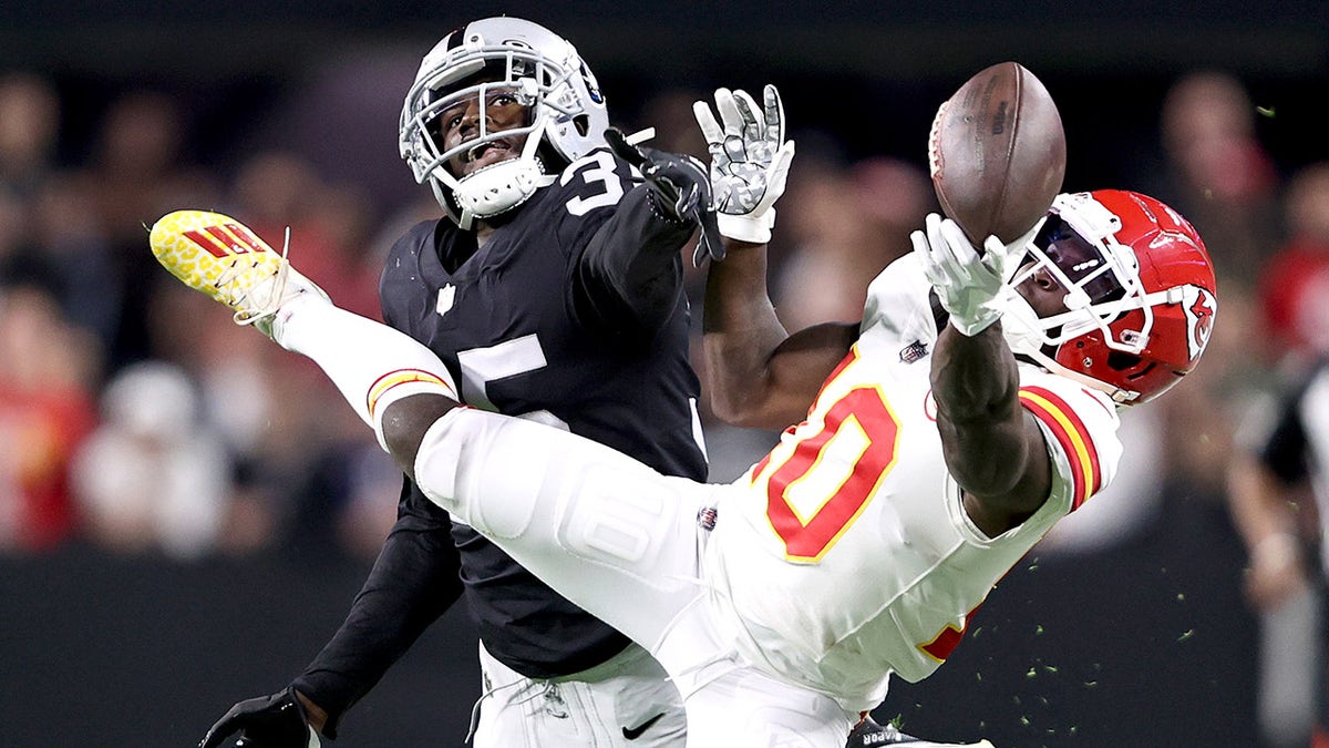 Tyreek Hill #10 of the Kansas City Chiefs and Brandon Facyson #35 of the Las Vegas Raiders try to catch the ball in the first quarter in the game at Allegiant Stadium on Nov. 14, 2021, in Las Vegas, Nevada.