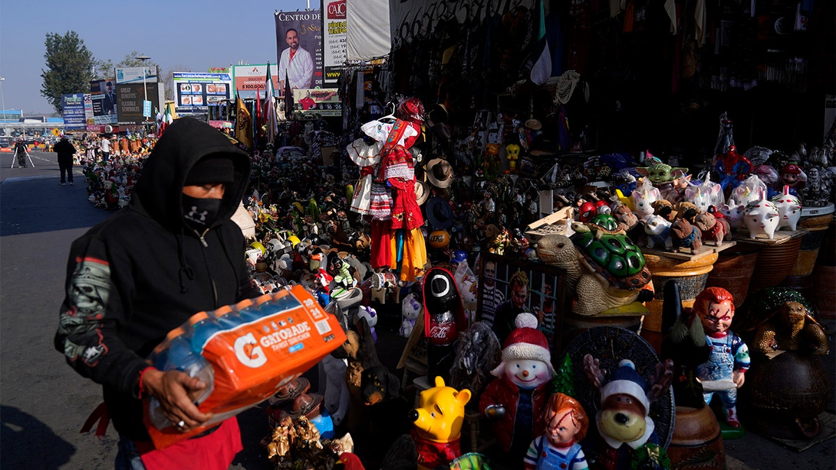A man prepares a stall of souvenirs and drinks to sell to people crossing into the United States at the San Ysidro Port of Entry, Monday, Nov. 8, 2021, in Tijuana, Mexico.