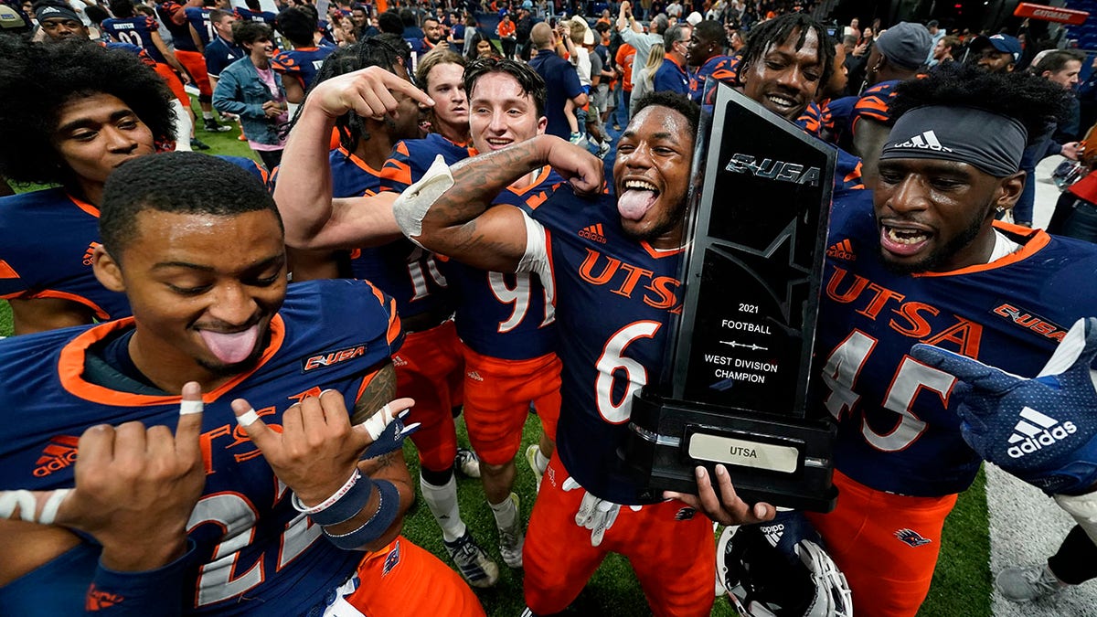 UTSA players celebrate with their conference trophy after their win over UAB in an NCAA college football game, Saturday, Nov. 20, 2021, in San Antonio.