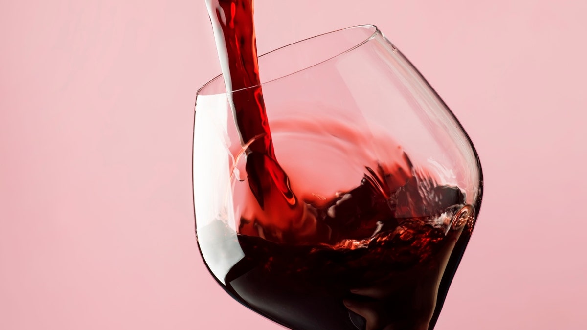 red wine being poured into glass stock image
