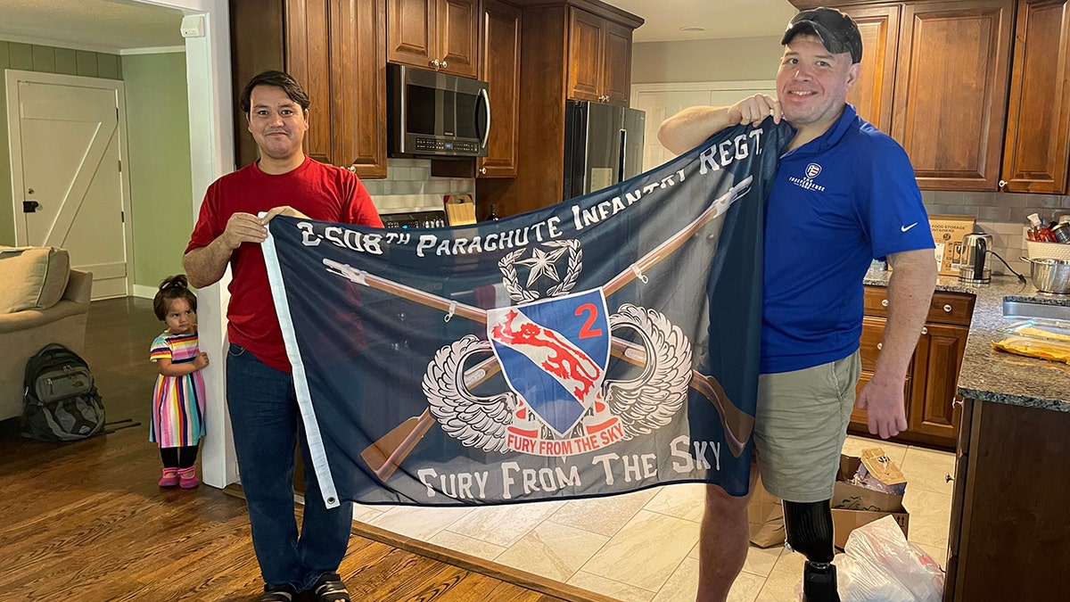 Afghan translator Johnny holds 508th Infantry Regiment flag with wounded veteran Mike Verardo