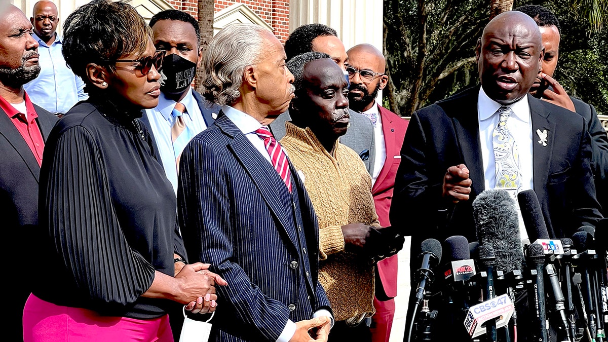 Family attorney Benjamin Crump speaks as Marcus Arbery (second from right), his former wife Wanda Cooper and Al Sharpton listen outside the Glynn County Courthouse on Nov. 10, 2021, in Brunswick, Georgia.