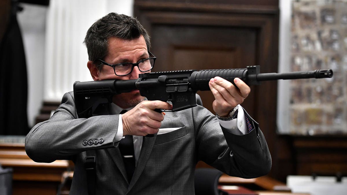Assistant District Attorney Thomas Binger holds Kyle Rittenhouse's gun as he gives the state's closing argument in Kyle Rittenhouse's trial at the Kenosha County Courthouse 