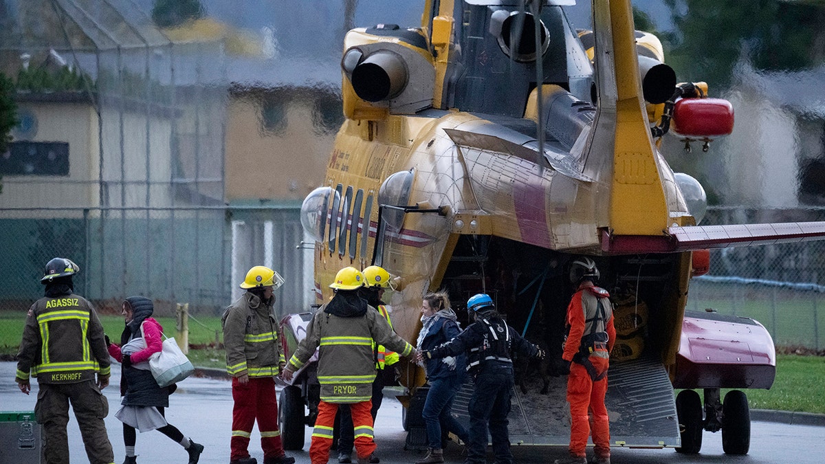 Search and rescue personnel help flood evacuees disembark from a helicopter in Agassiz, British Columbia, Monday, Nov. 15, 2021.