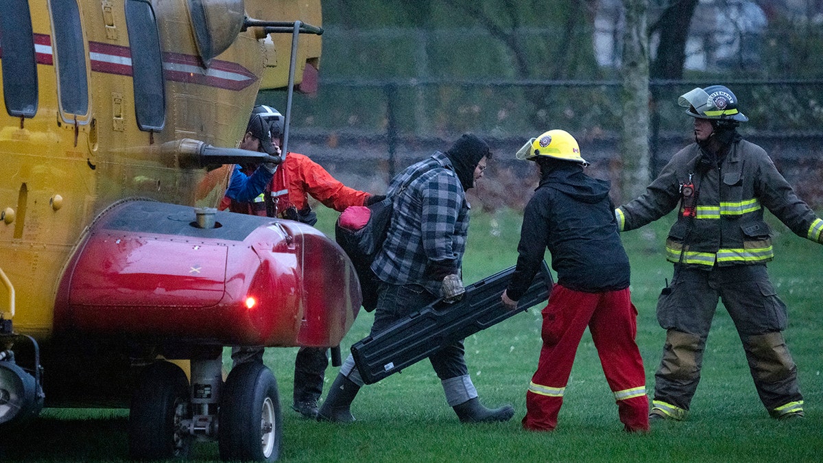 Search and rescue personnel help flood evacuees disembark from a helicopter in Agassiz, British Columbia, Monday, Nov. 15, 2021. 