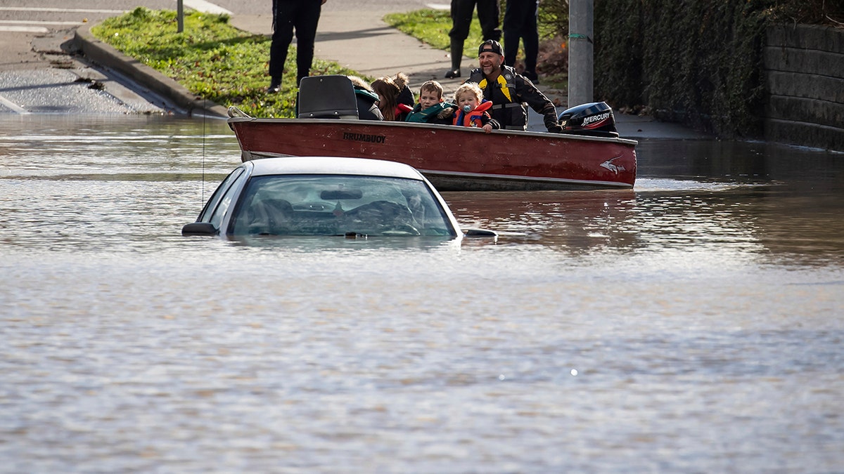 A woman and children who were stranded by high water due to flooding are rescued by a volunteer operating a boat Abbotsford, British Columbia, on Tuesday, Nov. 16, 2021. 