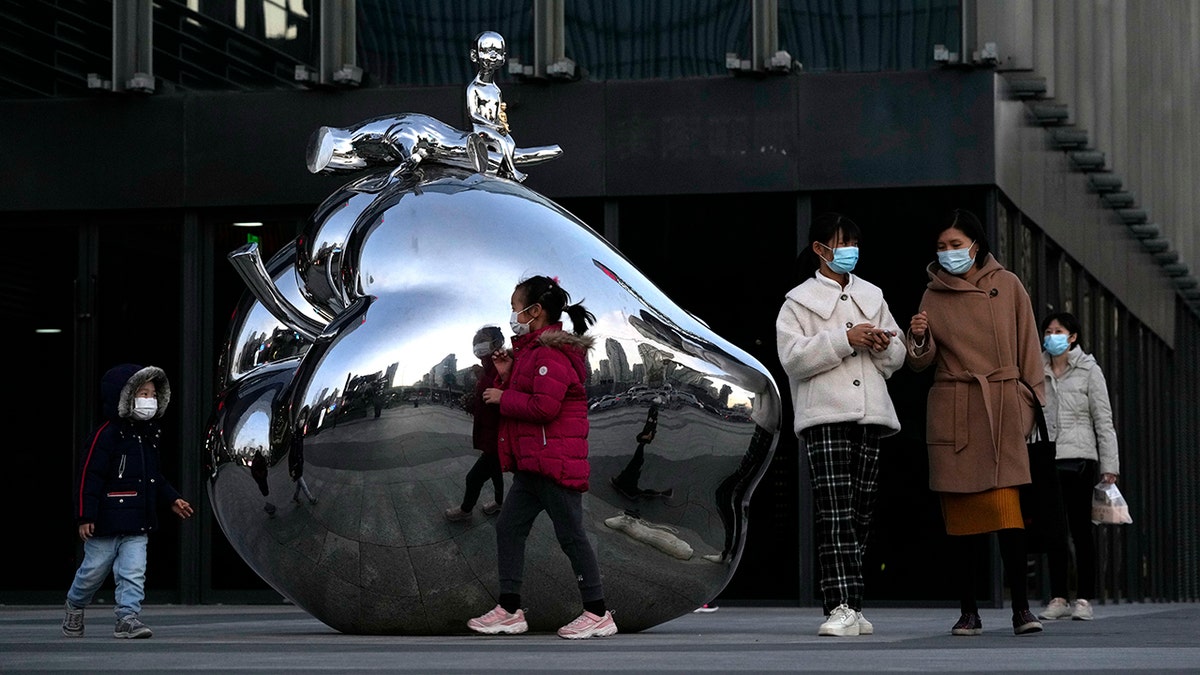 Residents wearing masks pass by artwork outside a mall in Beijing, China, on Nov. 13. 