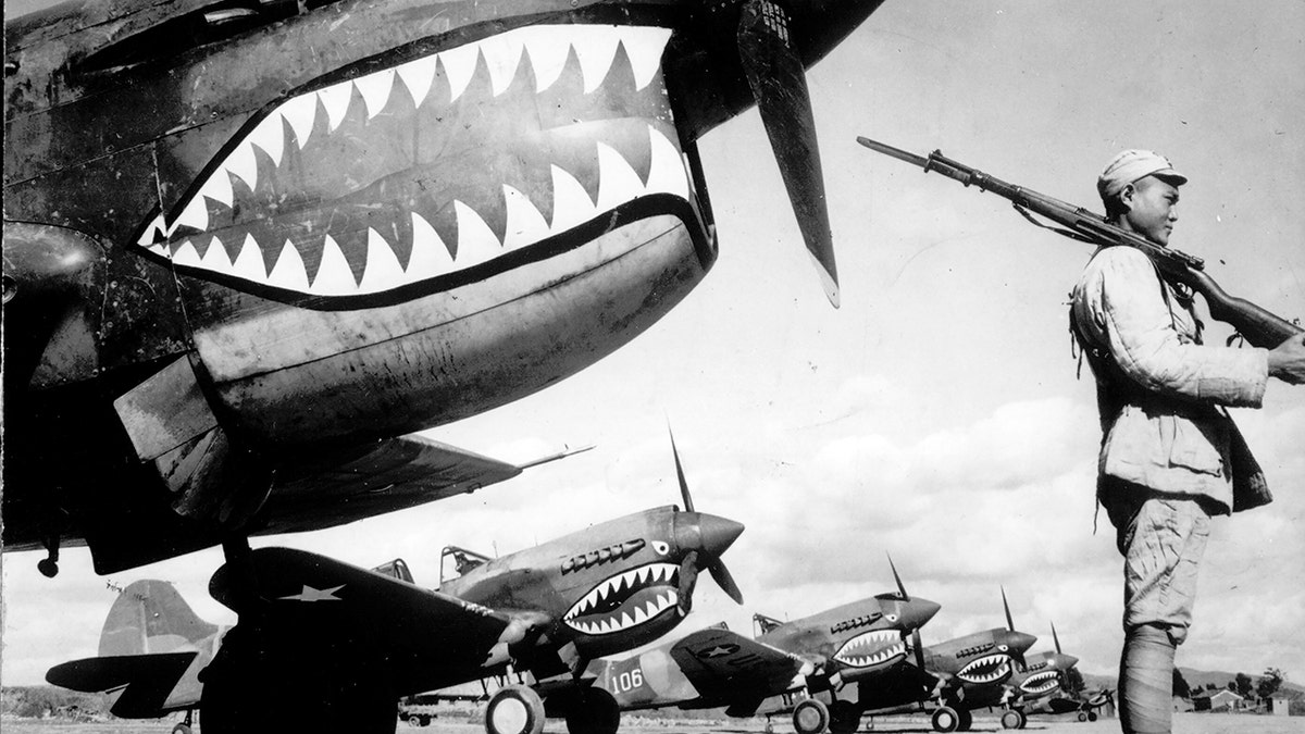 Guarded by a Chinese soldier, a squadron of Curtiss P-40 fighter planes, decorated with the typical shark face of the famed Flying Tigers, are lined up at an unknown airbase in China in 1943. 