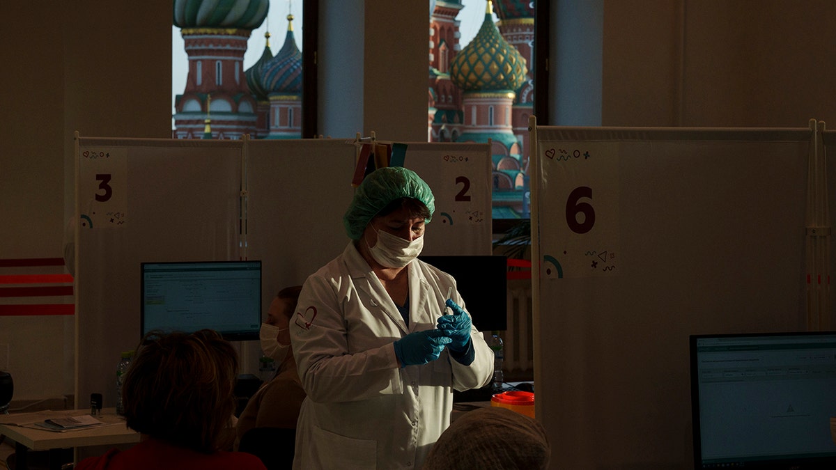 A medical worker prepares a shot of Russia's Sputnik Lite coronavirus vaccine at a vaccination center in the GUM, State Department store, in Red Square with the St. Basil Cathedral in the background in Moscow, Russia, on Oct. 26, 2021. 