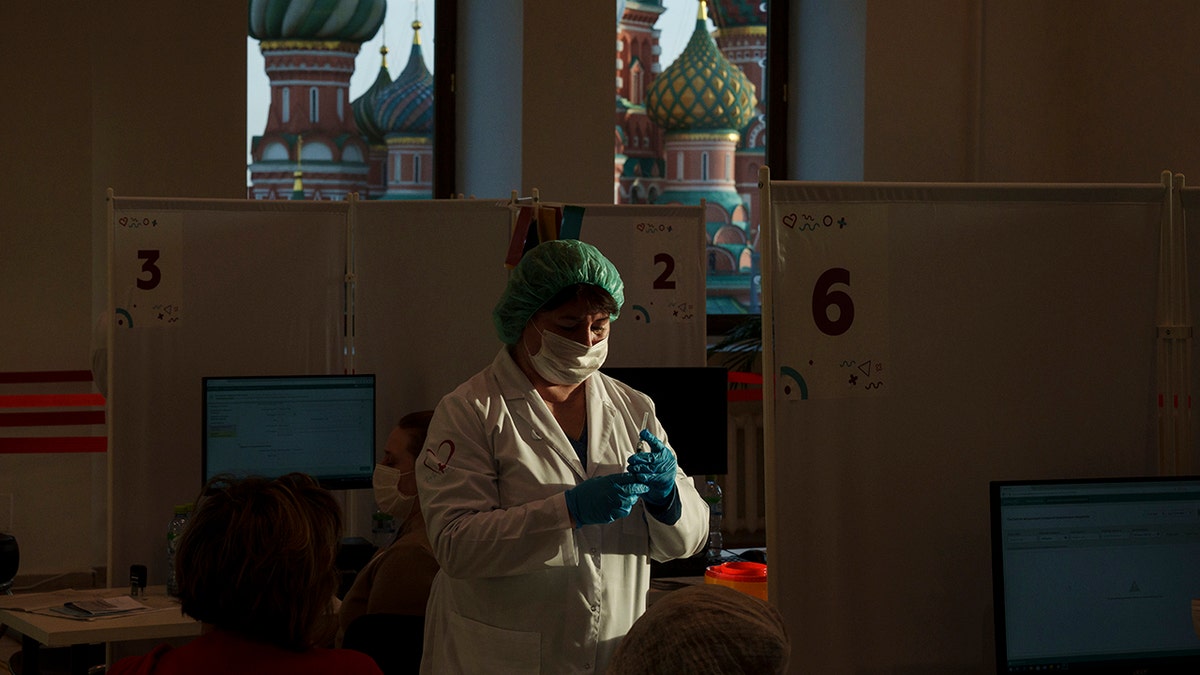 A medical worker prepares a shot of Russia's Sputnik Lite coronavirus vaccine at a vaccination center in the GUM, State Department store, in Red Square with the St. Basil Cathedral in the background in Moscow, Russia, on Oct. 26, 2021.?