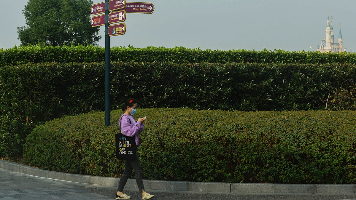 A woman wearing a face mask to help protect from the coronavirus walks near the closed Shanghai Disney Resort in Shanghai, China, on Monday.