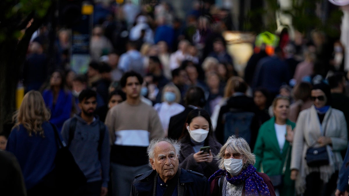 People wearing face masks walk along the Oxford Street shopping area of central London, Oct. 20, 2021.