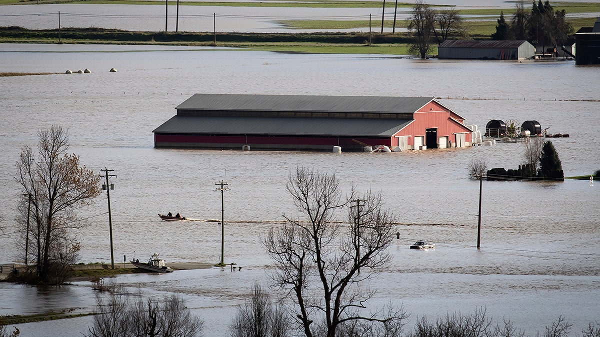 People in a boat travel across flooded farmland in Abbotsford, British Columbia, on Tuesday, Nov. 16, 2021. 