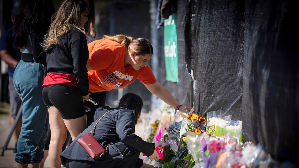 Stacey Sarmiento places flowers at a memorial in Houston on Sunday in memory of her friend, Rudy Pena, who died in a crush of people at the Astroworld music festival on Friday.
