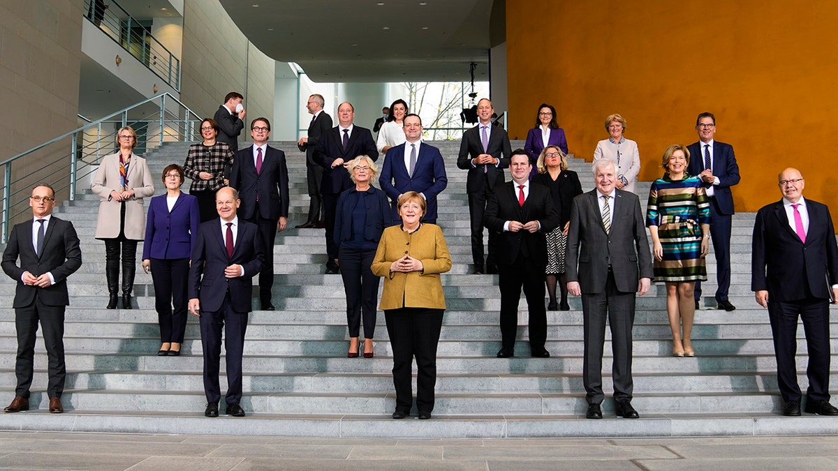 German Chancellor Angela Merkel, center, poses with her government after the Cabinet meeting at the chancellery in Berlin on Wednesday, Nov. 24, 2021. 