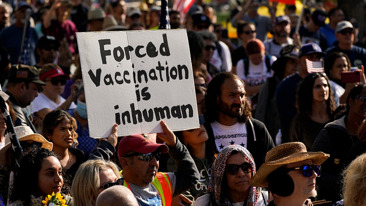 People listen to a speaker at a rally held to protest the city's new vaccine mandate on Monday, Nov. 8, 2021, in Los Angeles. (AP Photo/Jae C. Hong)
