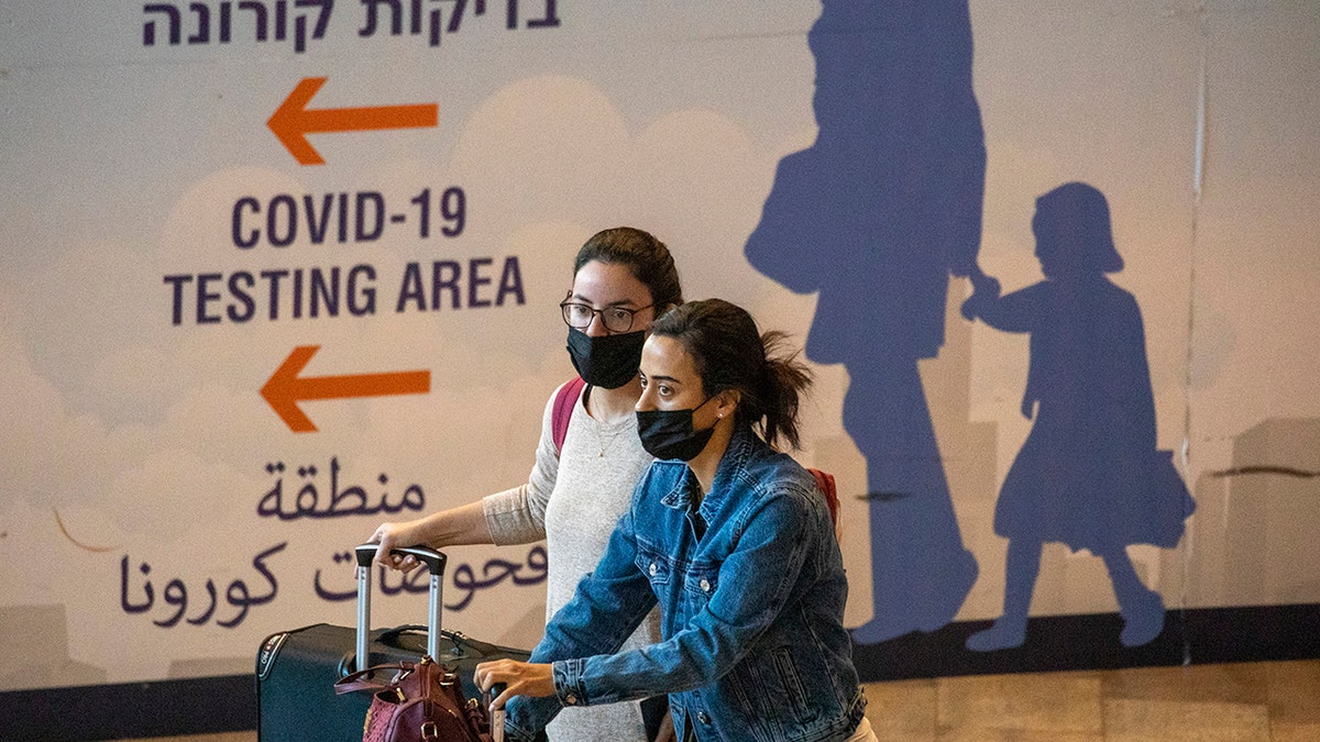 Travelers wearing protective face masks arrive at Ben Gurion Airport near Tel Aviv, Israel on Sunday, Nov. 28, 2021. 