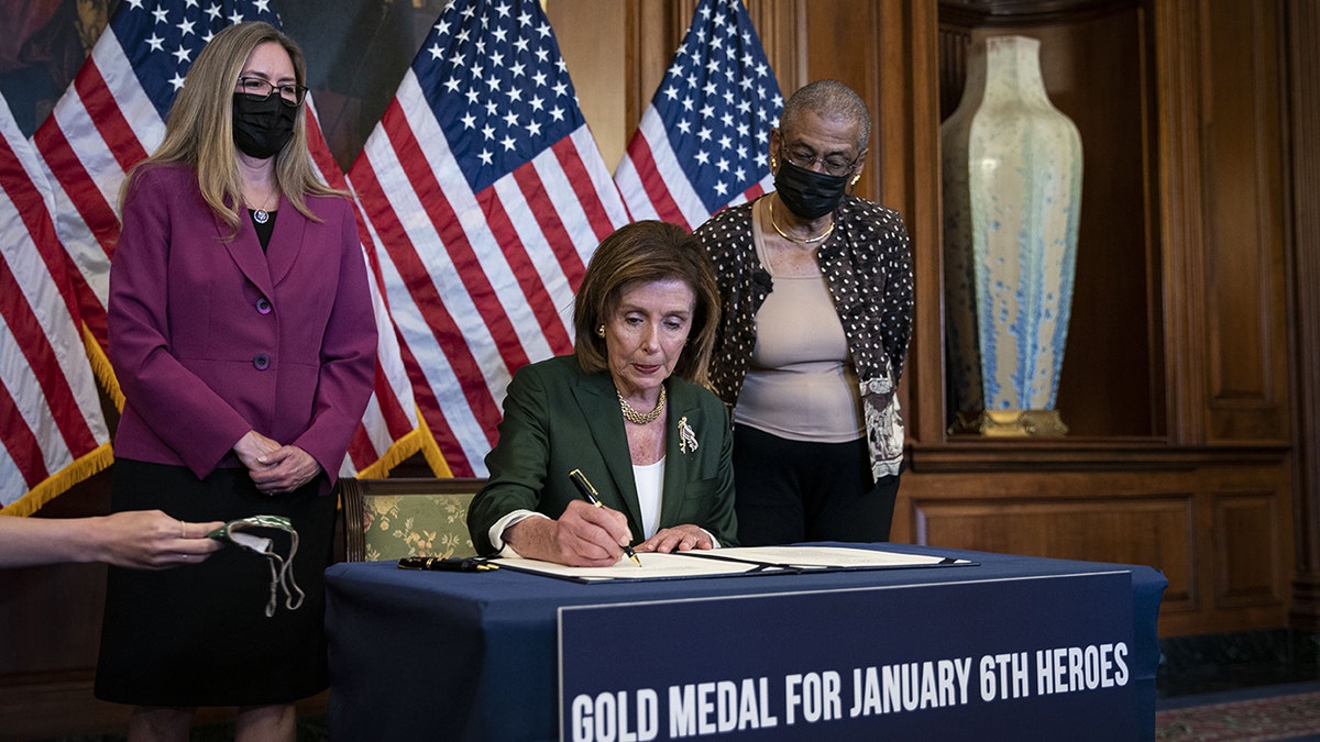 Speaker of the House Nancy Pelosi, D-Calif., signs H.R. 3325 during a bill enrollment ceremony with Rep. Jennifer Wexton, D-Va., left, and Rep. Eleanor Holmes Norton, D-D.C., at the U.S. Capitol on Wednesday, Aug. 4, 2021.