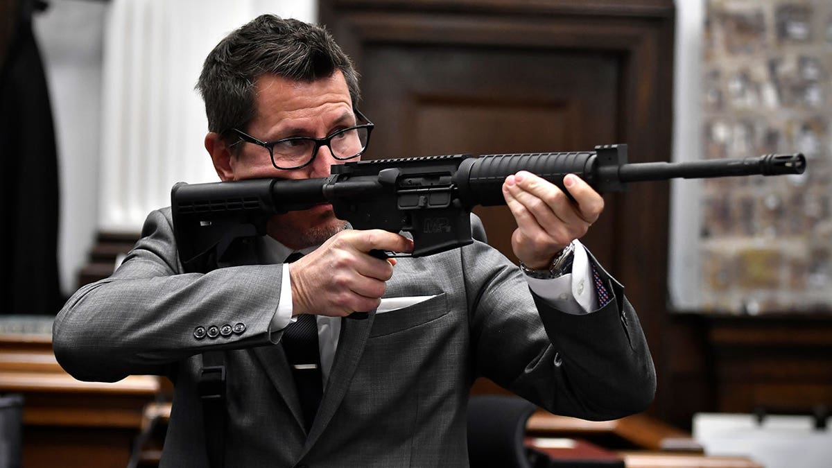 Assistant District Attorney Thomas Binger holds Kyle Rittenhouse's gun as he gives the state's closing argument in Kyle Rittenhouse's trial at the Kenosha County Courthouse in Kenosha, Wisconsin, on Monday, Nov. 15, 2021. 