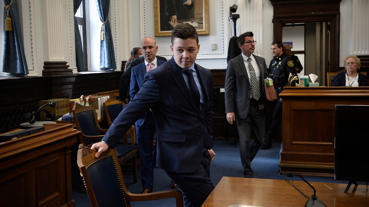 Kyle Rittenhouse, en el centro, retira su silla para una reunión convocada por el juez Bruce Schroeder durante su juicio en el juzgado del condado de Kenosha, en Kenosha, Wisconsin, el jueves 18 de noviembre de 2021. (Sean Krajacic/The Kenosha News vía AP, Pool)