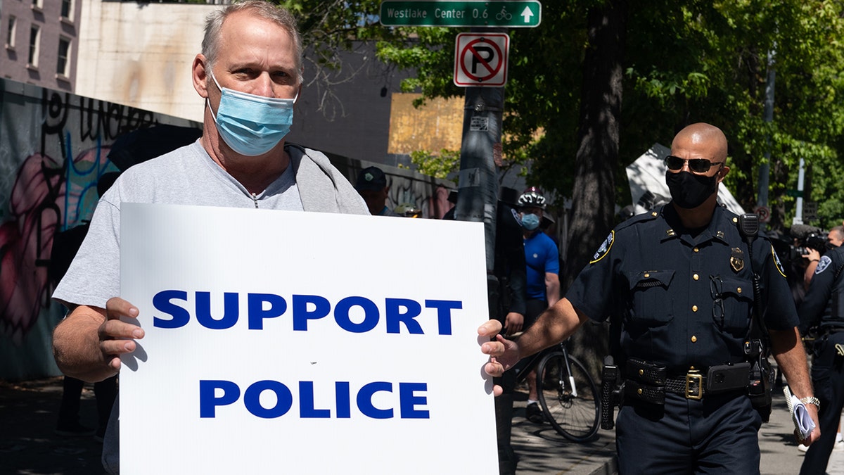 A man holds a sign during rally advocating to stop defunding of the Seattle Police Department on Aug. 9, 2020 at Seattle City Hall.