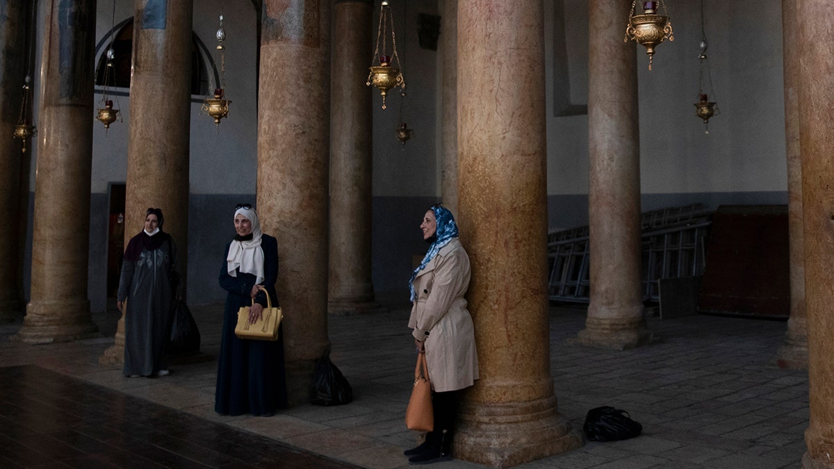 Tourists pose for a photo with renovated polished limestone columns, during a visit to the Church of the Nativity, in the West Bank city of Bethlehem, Tuesday, Nov. 16, 2021. 
