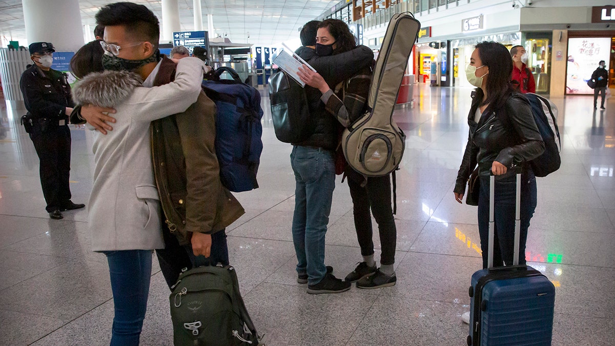 Wall Street Journal reporters, from right, Stephanie Yang, Julie Wernau and Stu Woo, embrace colleagues before their departure at Beijing Capital International Airport in Beijing on March 28, 2020. 